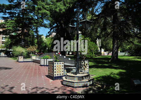 Sonne Schatten rot Mosaik Fliesen Weg mit weißen und blauen Mosaikfliesen angehoben Blume Betten Grasbäume, Plaza Espana, Mendoza, Argentinien Stockfoto