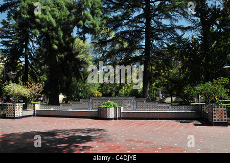 Sonne Schatten rot Mosaik Fliesen Weg, vorne weiße blaue Mosaik Fliesen Gartenmauer Blume Betten Bäume, Plaza Espana, Mendoza, Argentinien Stockfoto