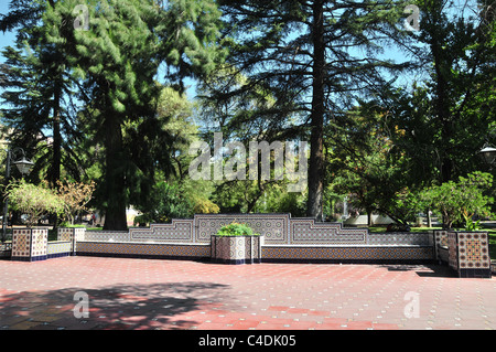 Sonnigen rot Mosaik Fliesen Weg, vorderen weißen blauen Mosaik Fliesen Gartenmauer Blume Betten Bäume, Plaza Espana, Mendoza, Argentinien Stockfoto