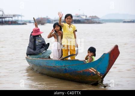 Eine kambodschanische Boot vierköpfige Familie mit einer Schlange, die Kamera auf dem Tonle Sap See in der Nähe von Siem Reap in Kambodscha winken Stockfoto