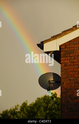 Ein Regenbogen an einem stürmischen Tag mit einem Haus und Satellitenschüssel im Vordergrund Stockfoto