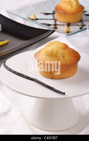 Vanille-Muffin auf eine Kuchenplatte und verschiedene Muffins im Hintergrund unscharf. Stockfoto