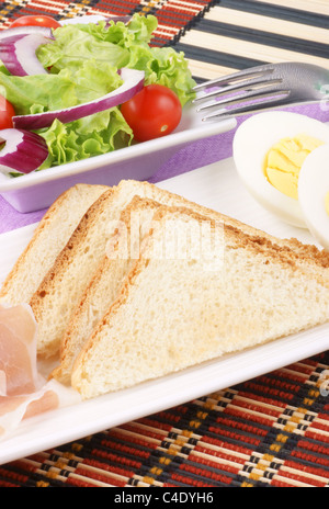 Snacks: geröstete Scheiben Brot, Schinken, gekochtes Ei und gemischtem Salat Stockfoto