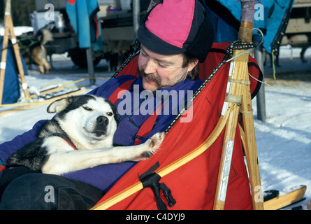 Eine liebevolle Musher ruht zusammen mit seinen Vorsprung im Hundeschlitten husky nach dem Training für den Iditarod Trail Sled Dog Race in der Nähe von Anchorage, Alaska, USA. Stockfoto