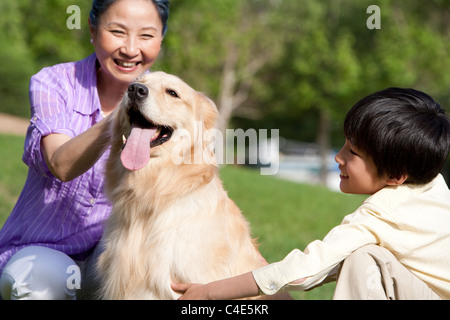 Großmutter und Enkel spielen mit Hund Stockfoto