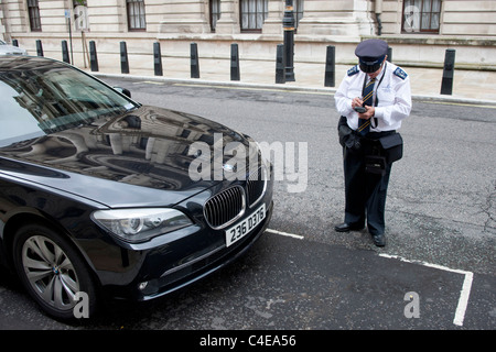 London Traffic Warden geben illegal geparkten BMW einen Parkschein lösen. Westminster, London Stockfoto