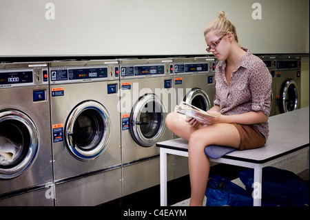 Mädchen-Lesebuch in Waschsalon Stockfoto