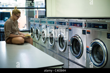 Junge Frau im Waschsalon lesen Stockfoto