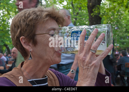 Ein weiblicher Touristen trinkt aus einer sehr großen Bierkrug im Biergarten Augustiner-Keller in München. Stockfoto