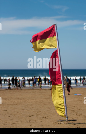 Warnung Flagge Marker auf der Blauen Flagge ausgezeichneten Sandstrand, im Sommer Surfer zum Meer unter gefährlichen Bedingungen in Woolacombe Bay Beach, Devon, Großbritannien Stockfoto