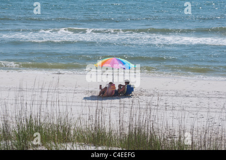 Golf-Strände Floridas Panhandle im St. Joseph Peninsula State Park. Paar erholsame unter einem Sonnenschirm an einem sonnigen Tag Stockfoto