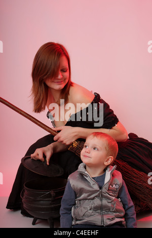 Eine Mutter verkleidet als Hexe für Halloween mit ihren jungen kleinen Sohn Süßes oder Saures auf All Hallows Eve einsatzbereit. Stockfoto