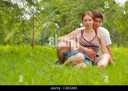 Junges attraktives Paar, sitzen auf einem Rasen in eine Wiese Stockfoto