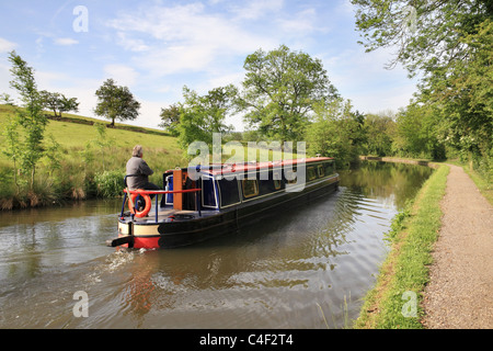 Ein Mann steuert seine schmale Kanalboot entlang dem Leeds und Liverpool Kanal in der Nähe von Skipton, Yorkshire, England, UK Stockfoto