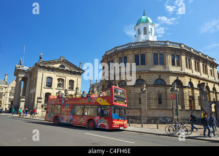 Touristenbus außerhalb Sheldonian Theatre und Clarendon Building, Broad Street, Oxford University, Innenstadt, Oxfordshir Stockfoto