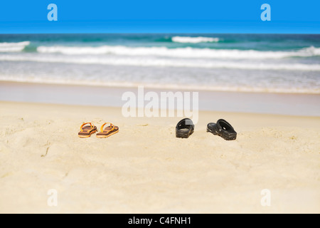 Zwei paar Flip-flops auf einem Sand von den tropischen Strand. Geringe Schärfentiefe. Stockfoto