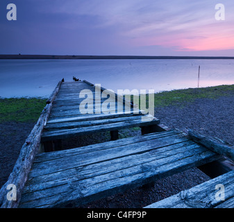 Heruntergekommen Sie Holzsteg auf The Fleet Lagune, mit Blick auf Chesil Beach, Dorset, England. Frühling 2011 (März). Stockfoto