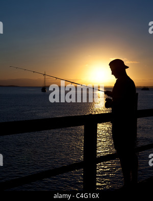 Ein Mann fischt bei Sonnenuntergang an einem Pier im Kingfisher Bay, Fraser Island. Queensland-Australien Stockfoto