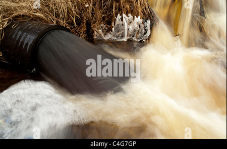 Drainpipe spuckt schwarzes Wasser aus, Finnland Stockfoto