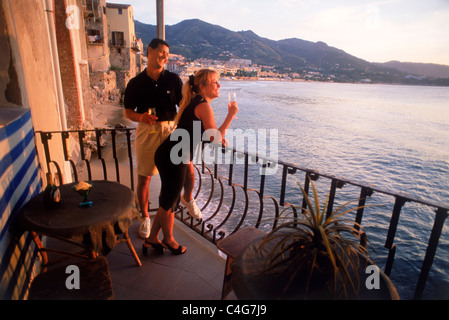 Paar auf Restaurant-Balkon über Mittelmeer bei Sonnenuntergang im Dorf von Cefalu auf Sizilien Stockfoto