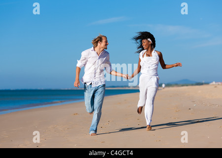 Paar - schwarze Frau und kaukasischen Mann - gehen und laufen auf einem Strand in ihren Urlaub Stockfoto