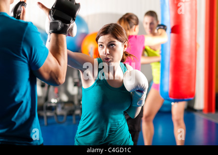Frau Boxer schlagen den Sandsack, unterstützt ihr trainer Stockfoto