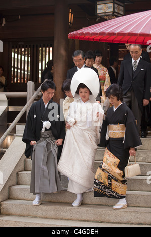 Meiji-Jingu Schrein steigt Braut sorgfältig Treppen mit Bräutigam neben ihr während Shinto Hochzeit Prozession, Tokio, Japan. Stockfoto