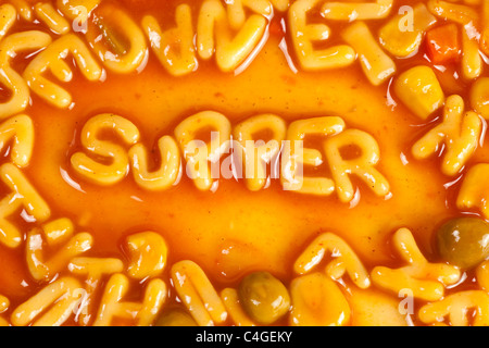 Alphabet geformten Nudeln bilden das Wort SUPPER in Tomatensauce Stockfoto