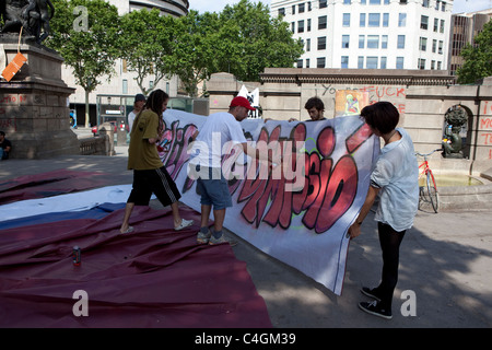 Regierungsfeindliche Demonstranten Sprühfarbe einen Banner in der spanischen Revolution Camp am Placa de Catalunya, Barcelona, Spanien. Stockfoto