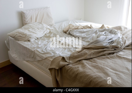 Ungemachten Bett in einem chaotischen Schlafzimmer Stockfoto