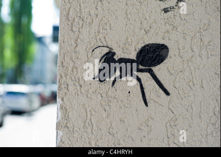 Graffiti zeigt eine Schwarze Ameise an der Ecke einer weißen Wand in München, Deutschland Stockfoto