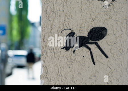 Graffiti zeigt eine Schwarze Ameise an der Ecke einer weißen Wand in München, Deutschland Stockfoto