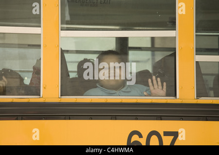 Lächelndes Mädchen schaut aus Schulbus Fenster Alond 5th Avenue in New York City. Stockfoto