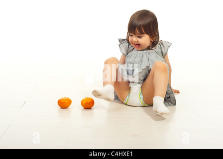 Kleinkind Mädchen Spaß mit zwei Mandarinen Früchte und am Boden Stockfoto