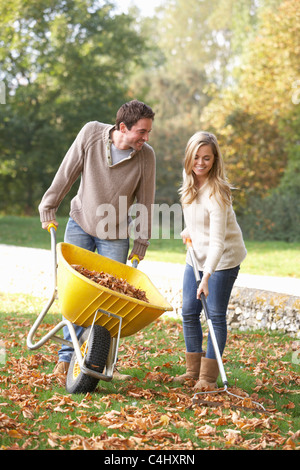 Junges Paar Rechen Herbst Blätter im Garten Stockfoto