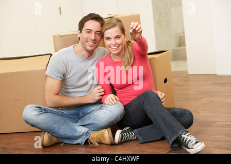 Junges Paar sitzen auf dem Boden um Boxen halten Schlüssel in der hand Stockfoto