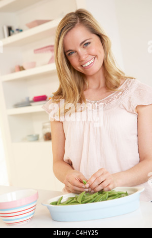 Junge Frau teilen Erbse in Küche Stockfoto