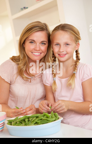 Junge Frau mit Kind teilen Erbse in Küche Stockfoto