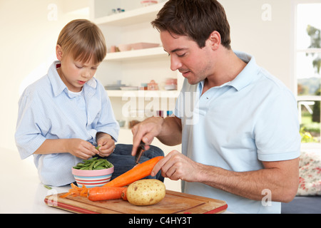 Glücklich Jüngling mit jungen schälen Gemüse in der Küche Stockfoto