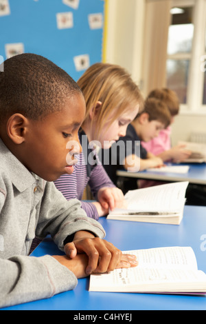 Schuljunge Lesebuch im Klassenzimmer Stockfoto