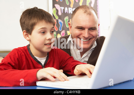 Schuljunge In es Klasse mit Computer mit Lehrer Stockfoto