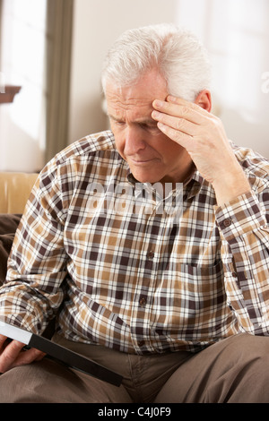 Trauriger Senior Mann Blick auf Foto im Rahmen Stockfoto