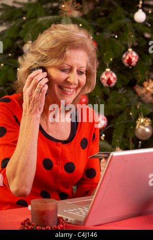 Senior Woman Online-Shopping für Weihnachtsgeschenke auf Handy Stockfoto