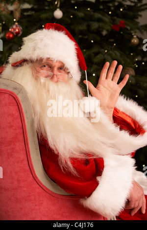 Weihnachtsmann sitzt im Sessel vor Weihnachtsbaum Stockfoto