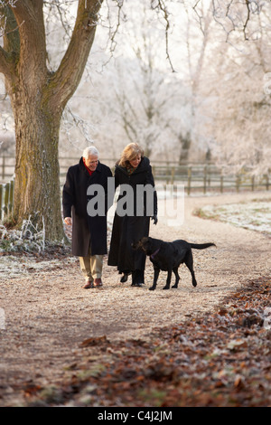 Älteres Paar auf Winter-Spaziergang mit Hund durch frostige Landschaft Stockfoto