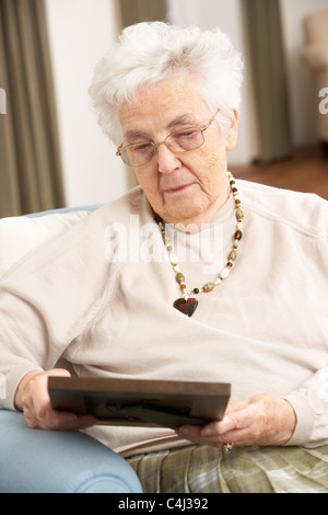 Senior Woman Looking At Foto im Rahmen Stockfoto