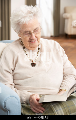 Ältere Frau im Sessel zu Hause Lesebuch entspannen Stockfoto