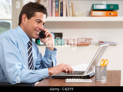 Mann arbeitet von zu Hause mit Laptop auf Handy Stockfoto