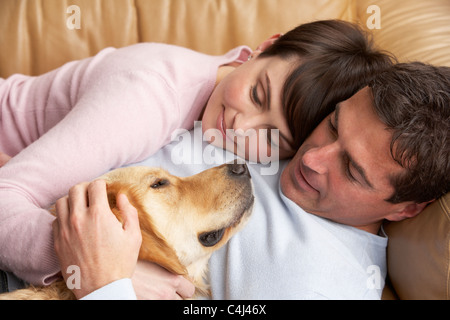 Porträt von paar gemütlich auf Sofa mit Hund zu Hause Stockfoto