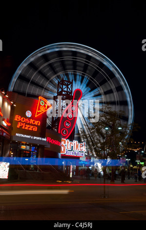 Die helle, bunte Lichter der Clifton Hill in der Nacht mit beweglichem Riesenrad im Hintergrund. Stockfoto